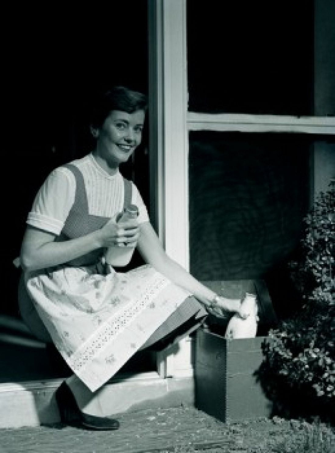 Young woman collecting milk bottles outside home Canvas Art - (24 x 36)