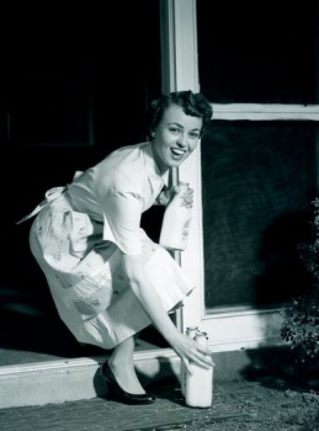 Young woman collecting milk bottles outside home Canvas Art - (24 x 36)