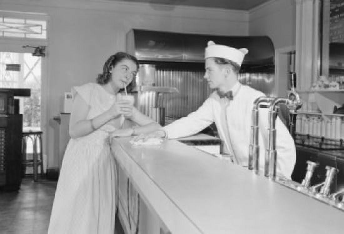 Young woman drinking milkshake at bar counter with barman Canvas Art - (24 x 36)