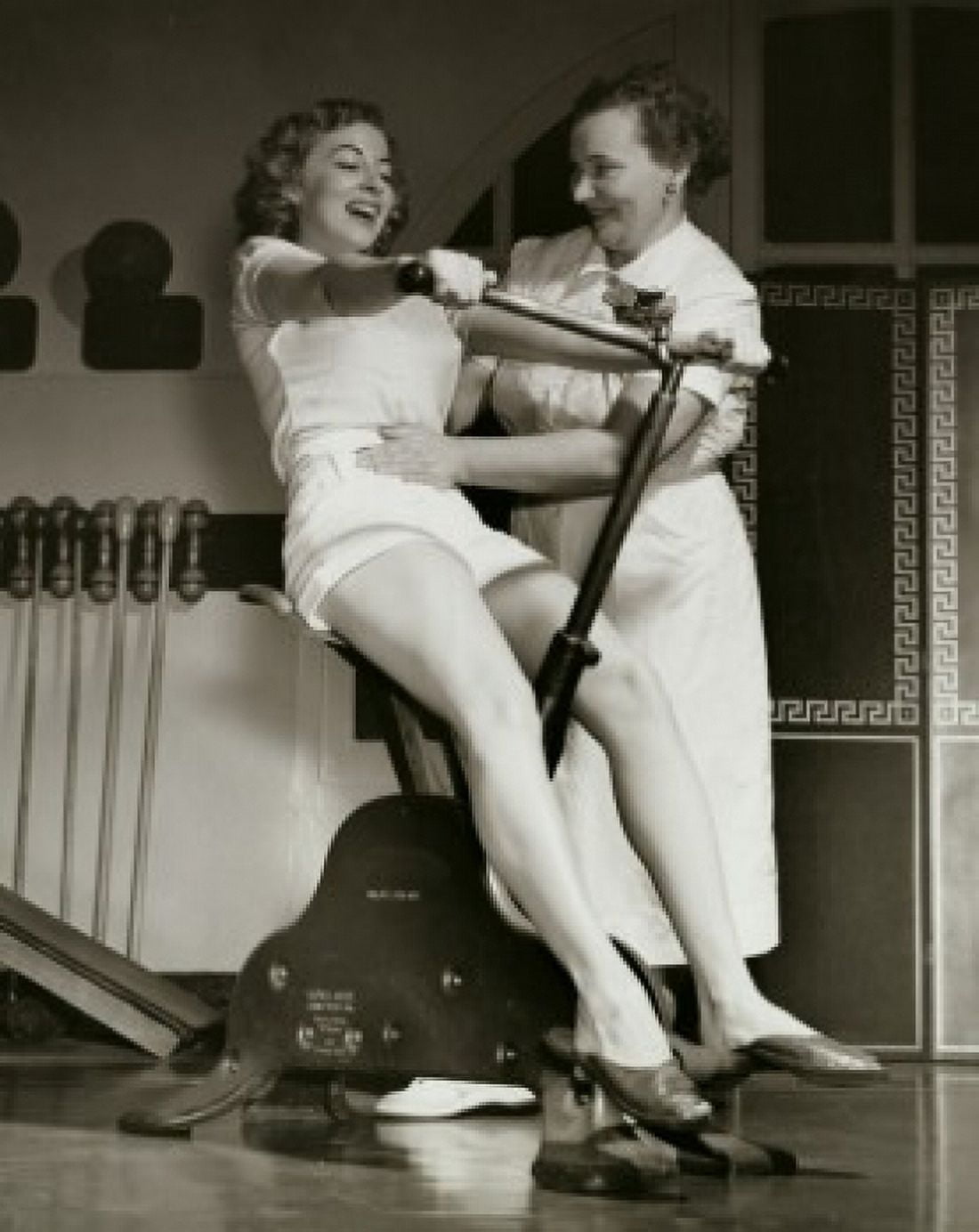 Young woman exercising on an exercise bike with her instructor touching her abdomen Canvas Art - (24 x 36)