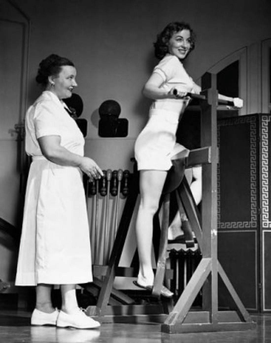 Young woman exercising on an exercise machine with her instructor standing behind her Canvas Art - (18 x 24)