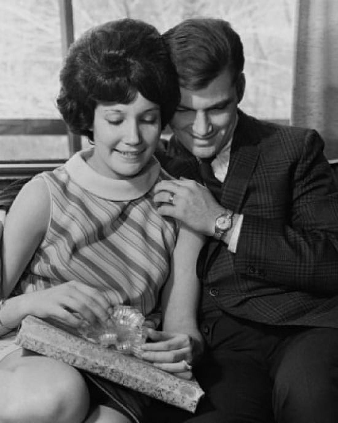 Young woman holding a gift and sitting with a young man Canvas Art - (24 x 36)