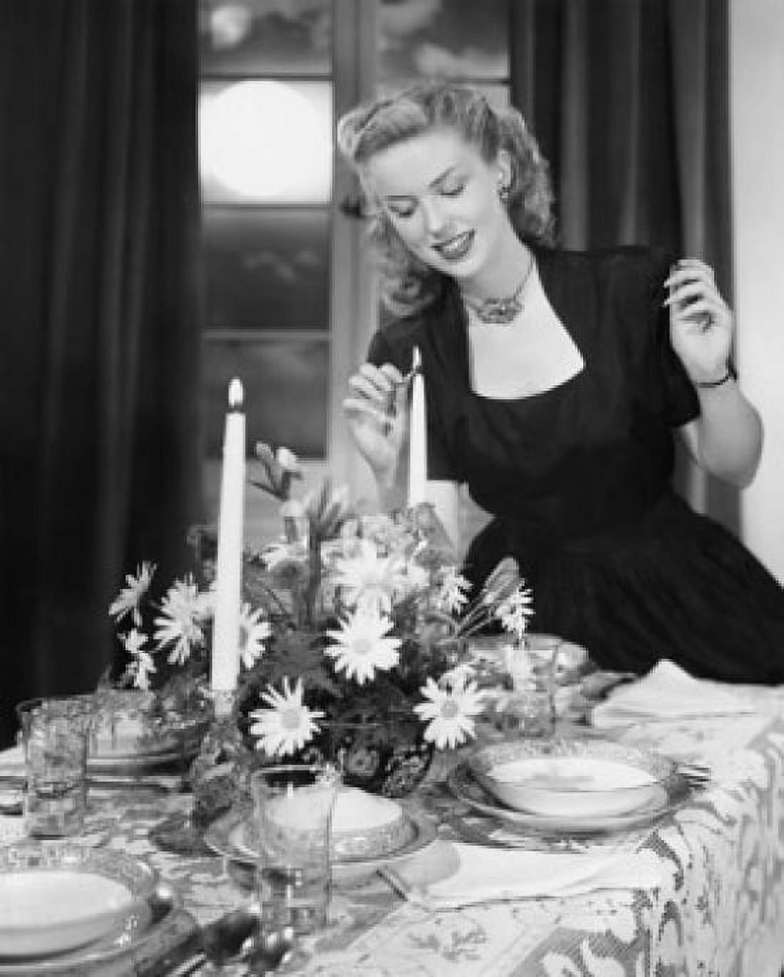 Young woman lighting a candle at a dining table Canvas Art - (18 x 24)