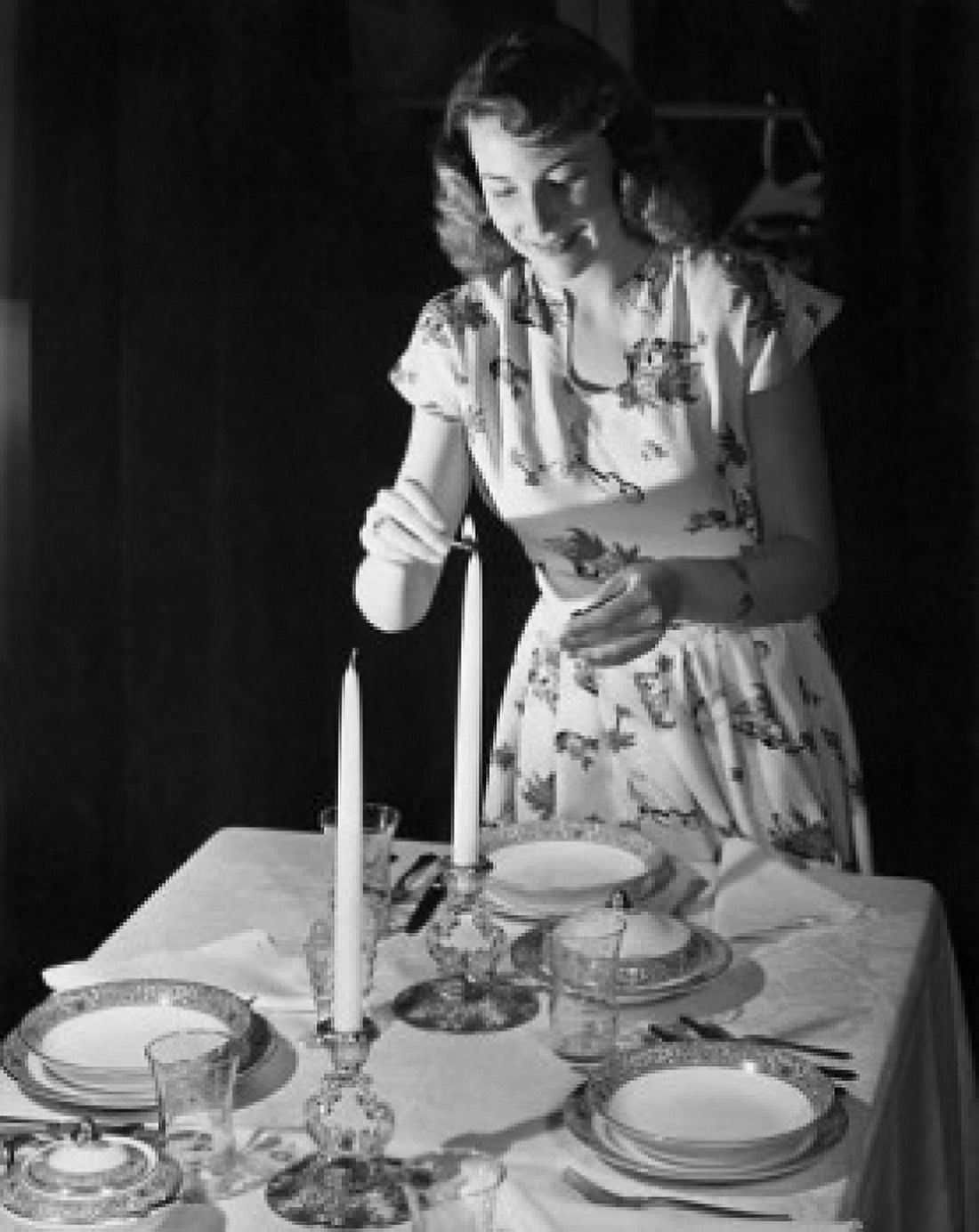 Young woman lighting a candle at a dining table Canvas Art - (24 x 36)