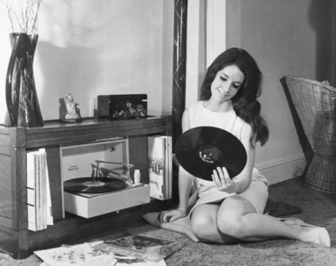 Young woman looking at a record and smiling Canvas Art - (24 x 36)