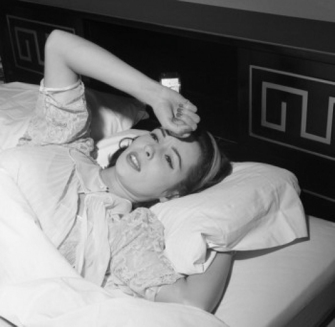 Young woman lying in bed with hand on forehead Canvas Art - (24 x 36)