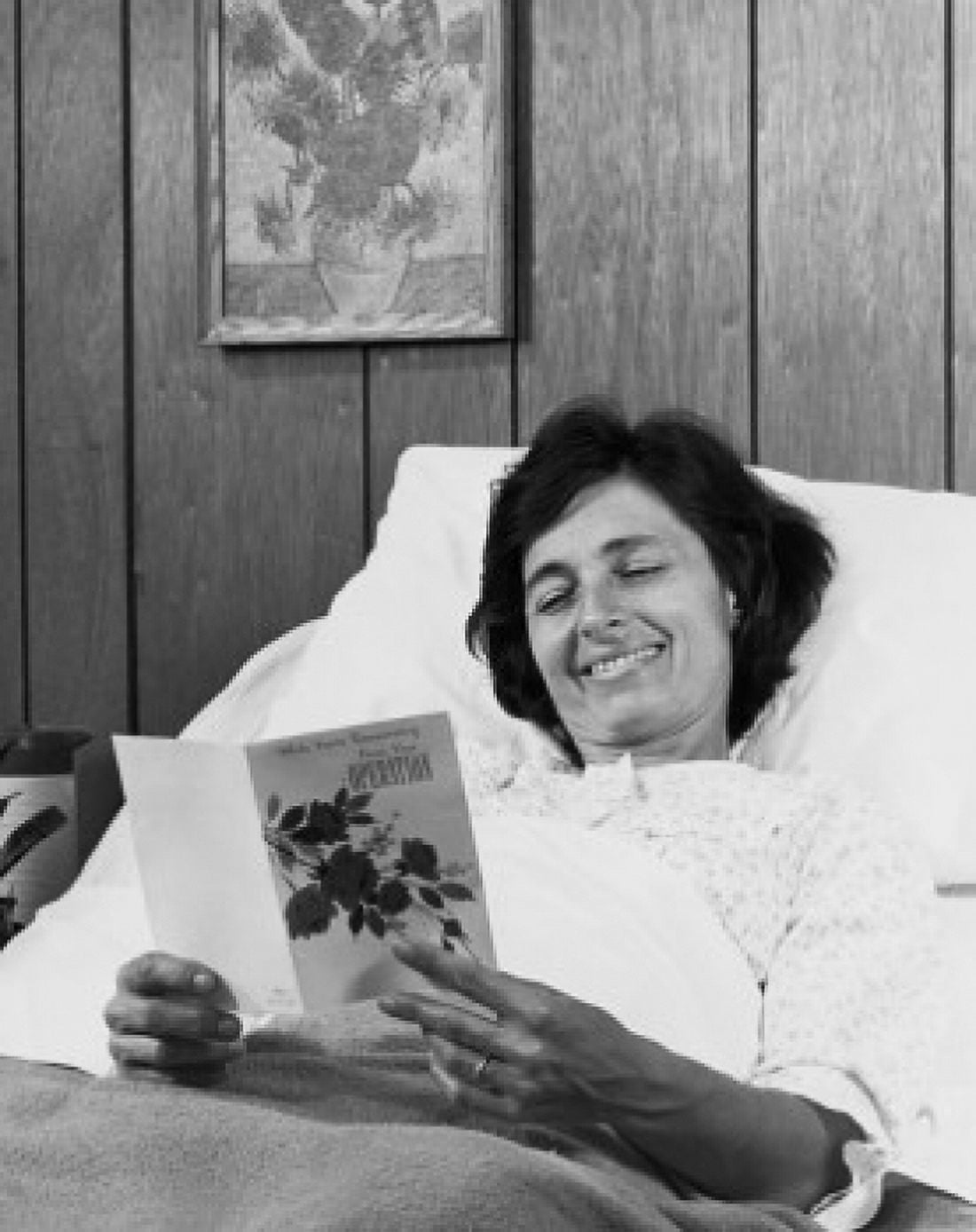 Young woman lying on the bed and reading a get well card Canvas Art - (24 x 36)