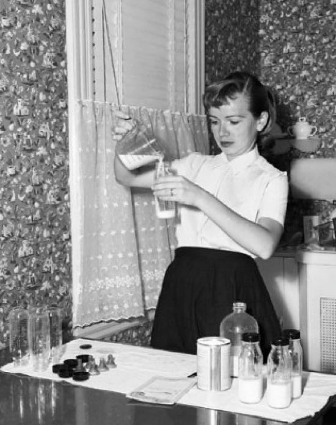 Young woman pouring milk into a baby bottle Canvas Art - (18 x 24)