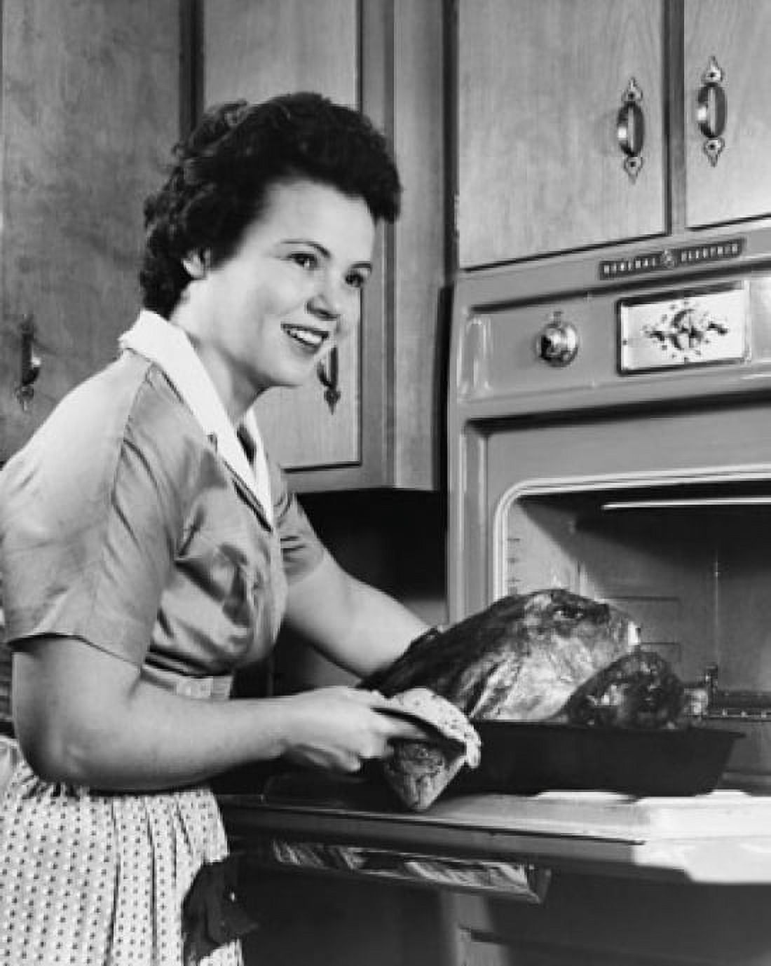 Young woman putting a turkey into an oven Canvas Art - (18 x 24)