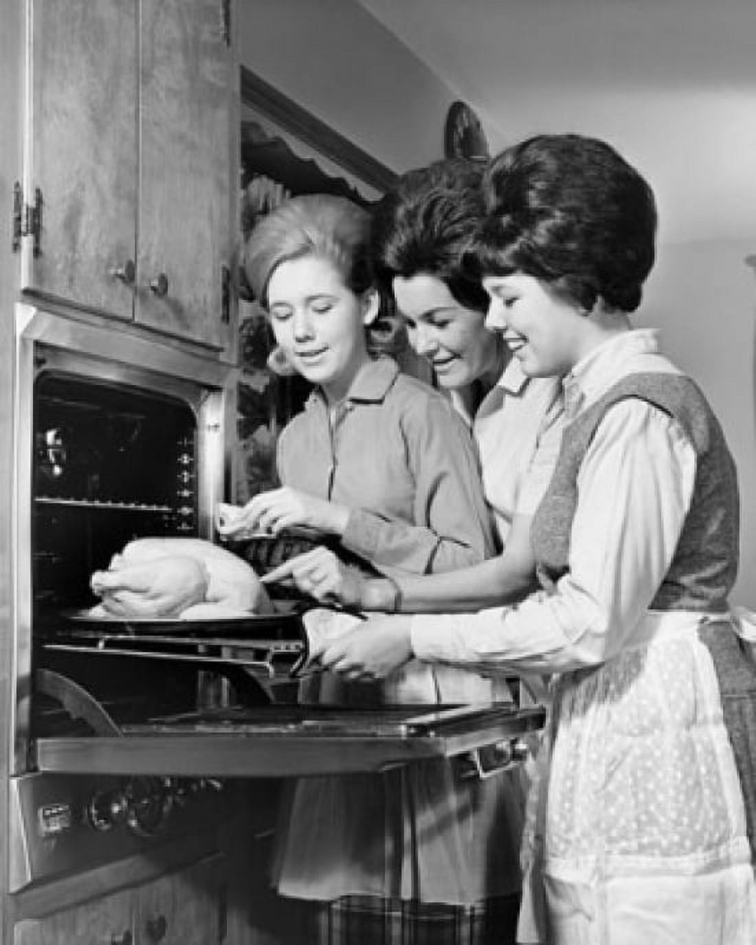 Young woman putting a turkey into an oven with two young women standing beside her Canvas Art - (24 x 36)