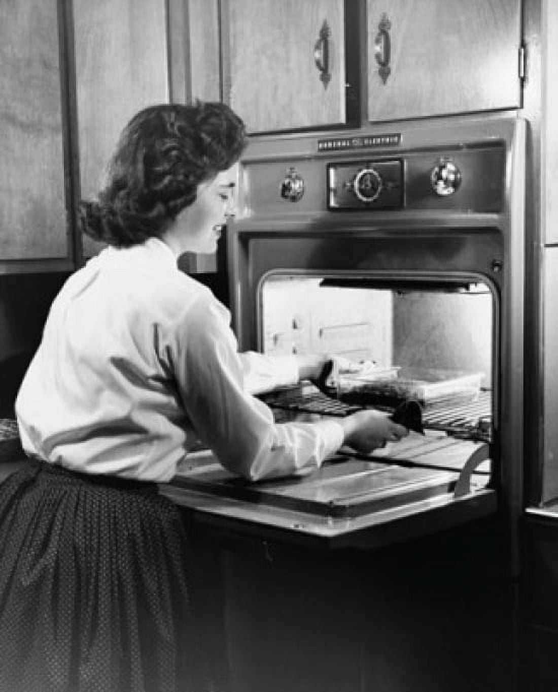 Young woman putting food into an oven Canvas Art - (18 x 24)