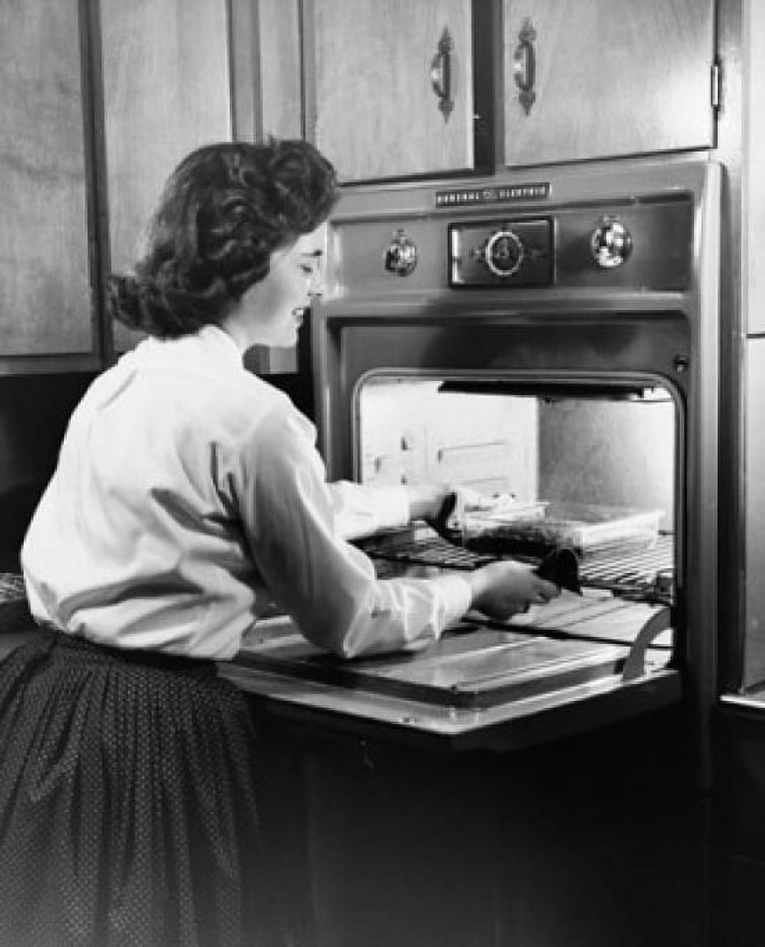 Young woman putting food into an oven Canvas Art - (24 x 36)