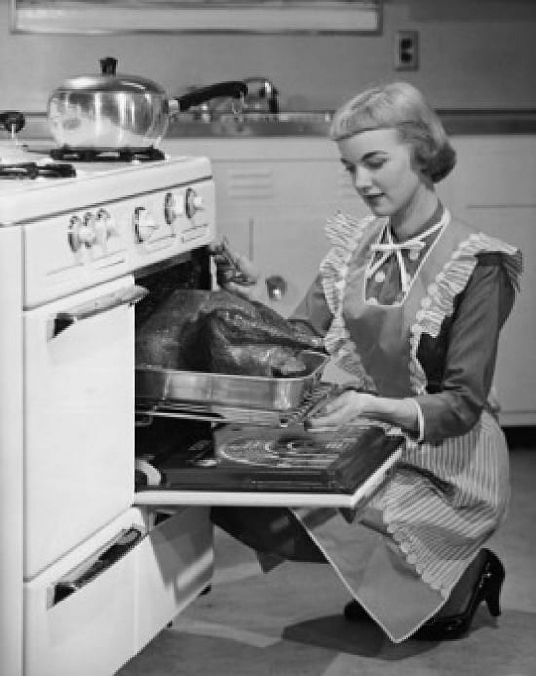 Young woman putting turkey into oven Canvas Art - (18 x 24)