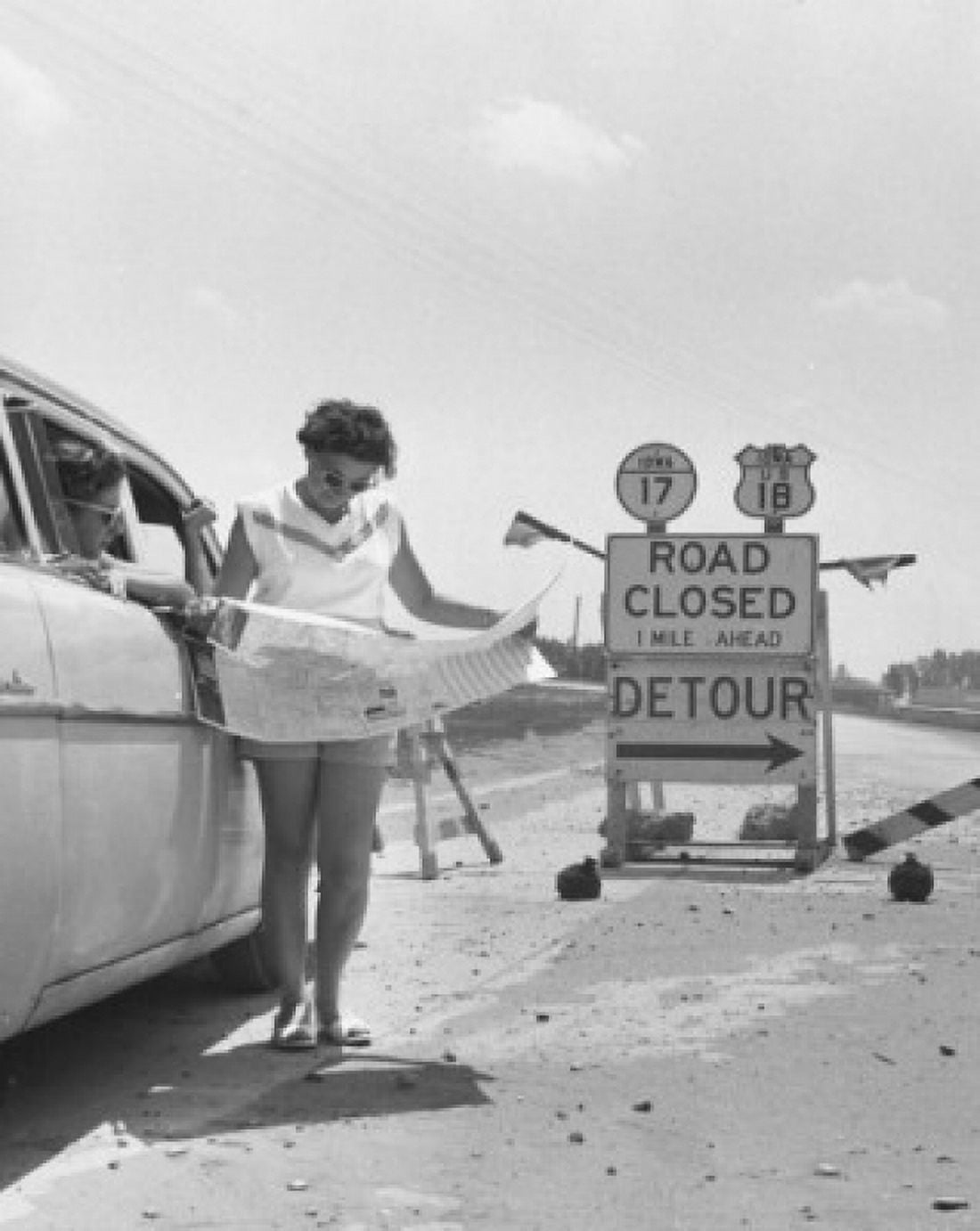 Young woman reading a map in front of a road closed sign Canvas Art - (18 x 24)