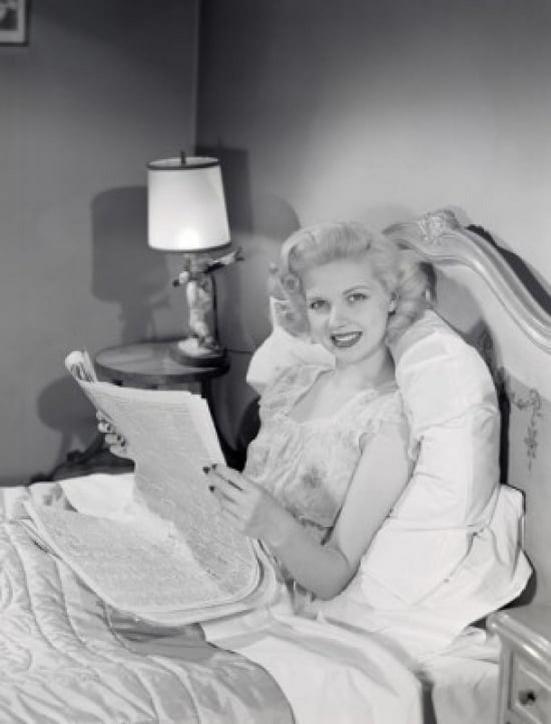 Young woman reading newspaper in bed Canvas Art - (24 x 36)