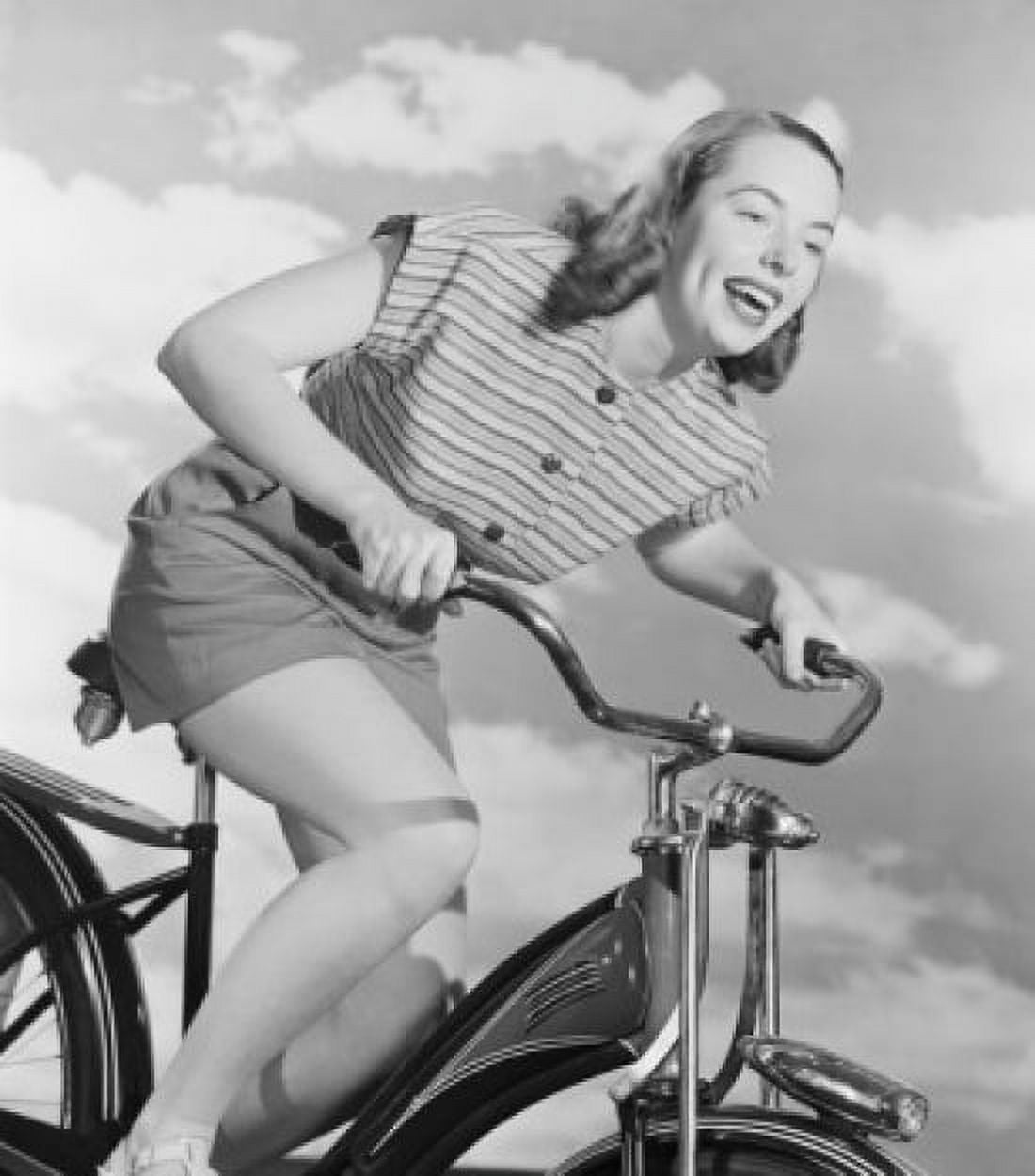 Young woman riding bicycle against cloudy sky Canvas Art - (24 x 36)