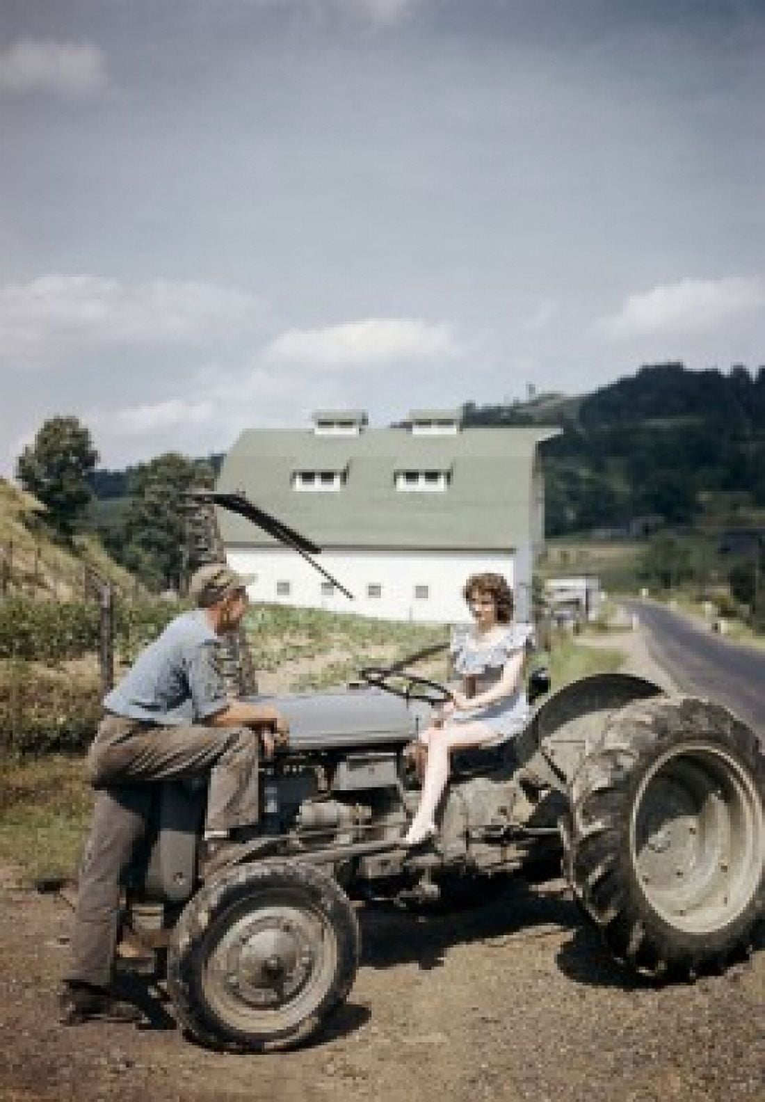 Young woman sitting on a tractor with a young man standing in front of her Canvas Art - (18 x 24)