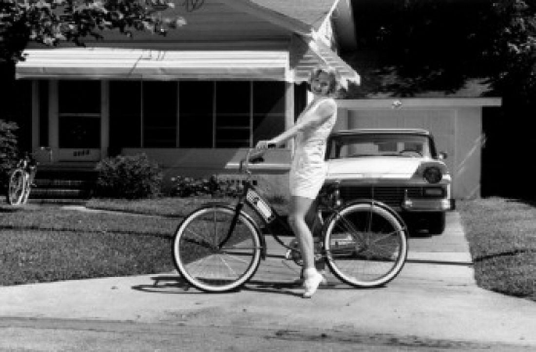 Young woman sitting on bicycle in driveway Canvas Art - (18 x 24)
