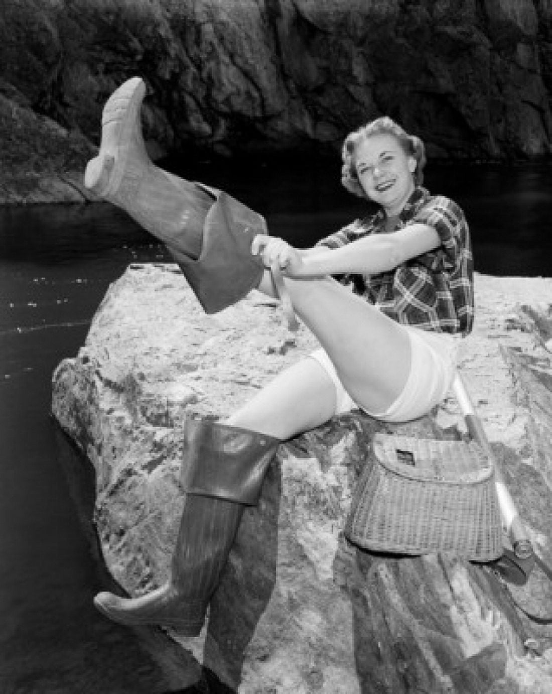 Young woman sitting on rock putting on wellington boots Canvas Art - (24 x 36)