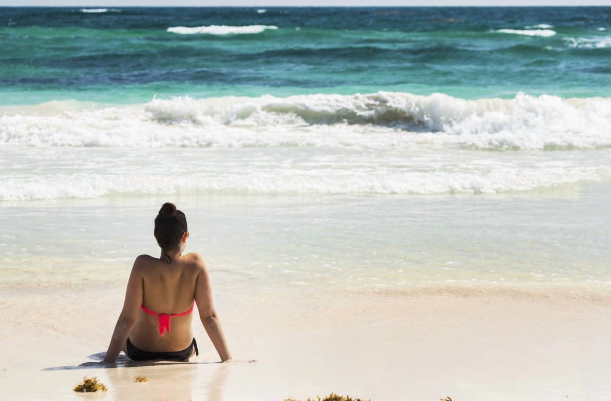 Young woman sitting on sandy beach in water looking out at waves coming in and blue sky Akumal Quintana Roo Mexico Canvas Art - Michael Interisano Design Pics (38 x 24)