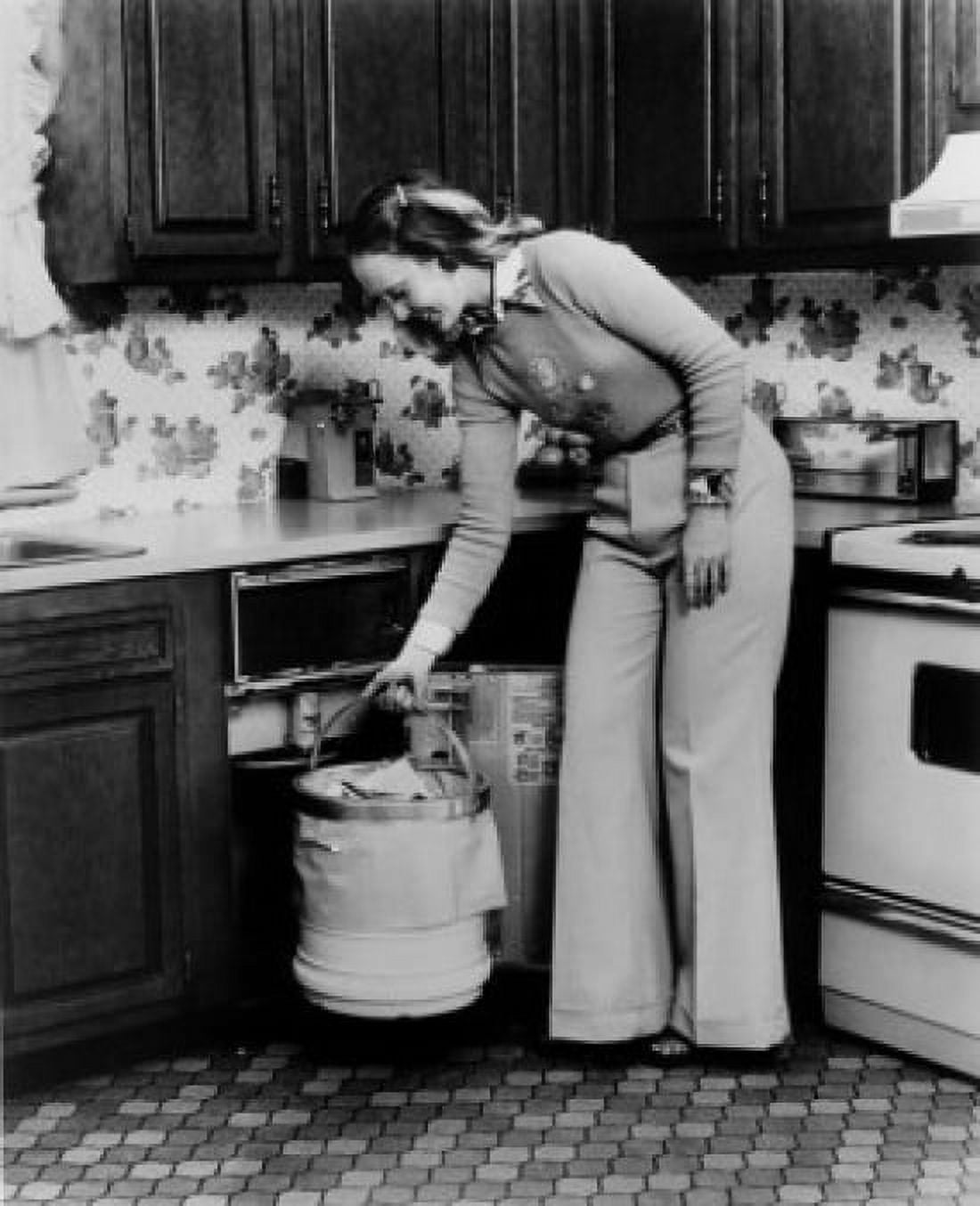 Young woman standing in the kitchen holding a garbage bin Canvas Art - (24 x 36)