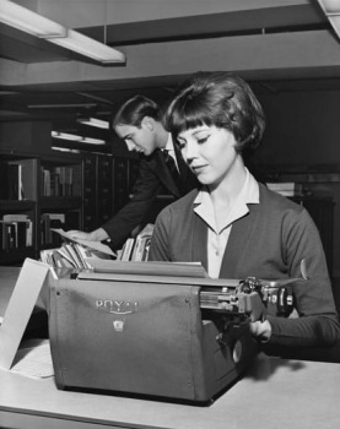 Young woman typing a document on a typewriter in an office Canvas Art - (18 x 24)