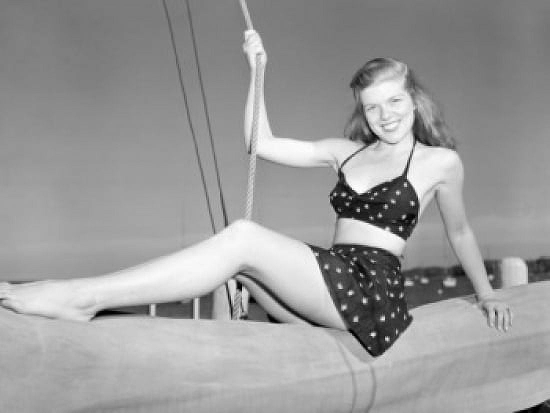 Young woman wearing bikini sitting on rolled up sail Canvas Art - (24 x 36)