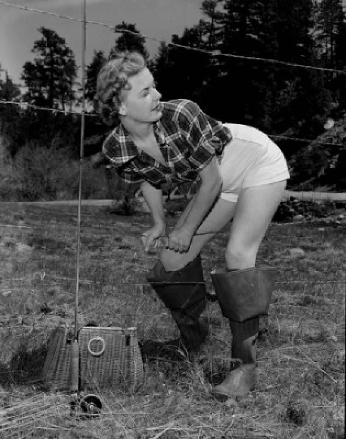 Young woman with fishing rod and basket crossing barbed wire fence Canvas Art - (24 x 36)