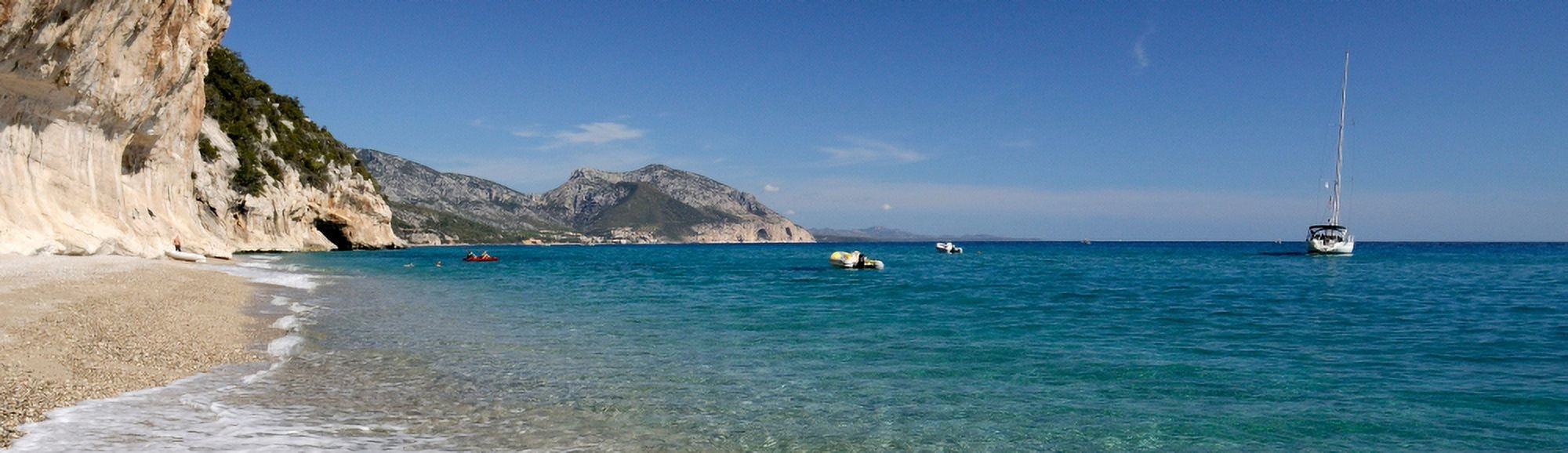 Zodiacs and sailboat in the sea Cala Luna Cala Gonone Nuoro Sardinia Italy Canvas Art - Panoramic Images (27 x 9)