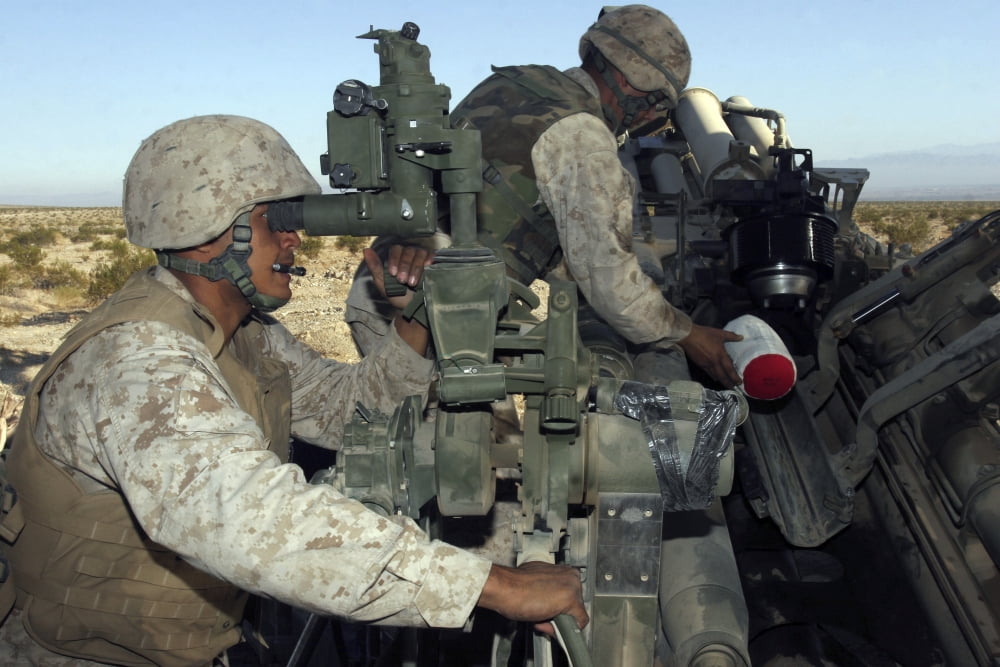 A cannoneer looks through the sights of the M777 Lightweight Howitzer as another crewman inserts a bag of gunpowder into the barrel Canvas Art - Stocktrek Images (34 x 23)