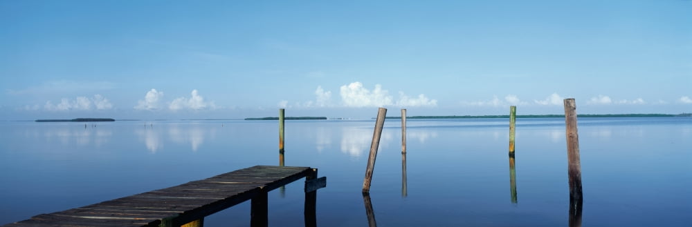 This is the morning view of Pine Island Sound Its pier juts out from the left side with wooden pylons standing up out of the water near the shore Canvas Art - Panoramic Images (27 x 9)