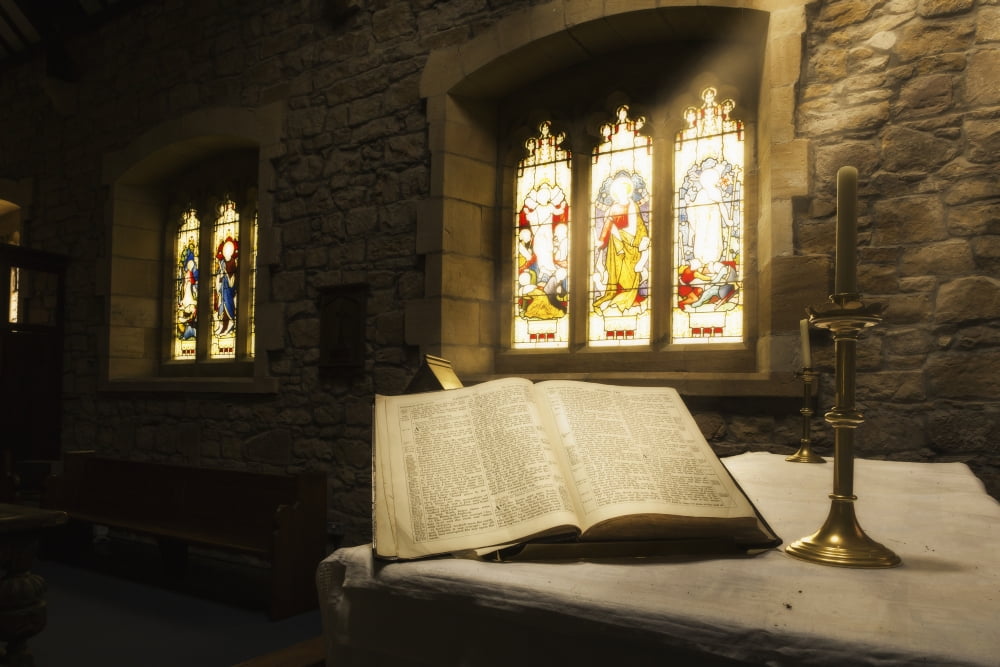 An open Bible on display in a church with colourful stained glass windows Bamburgh Northumberland England Canvas Art - John Short Design Pics (19 x 12)