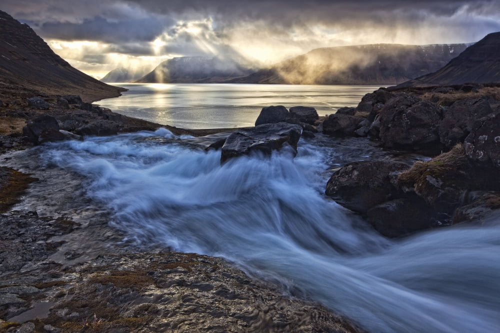 A stormy sky breaks above the Arnarfjorour fjord at sunset as waterfall Dynjandi flows into it Iceland Canvas Art - Robert Postma Design Pics (34 x 22)