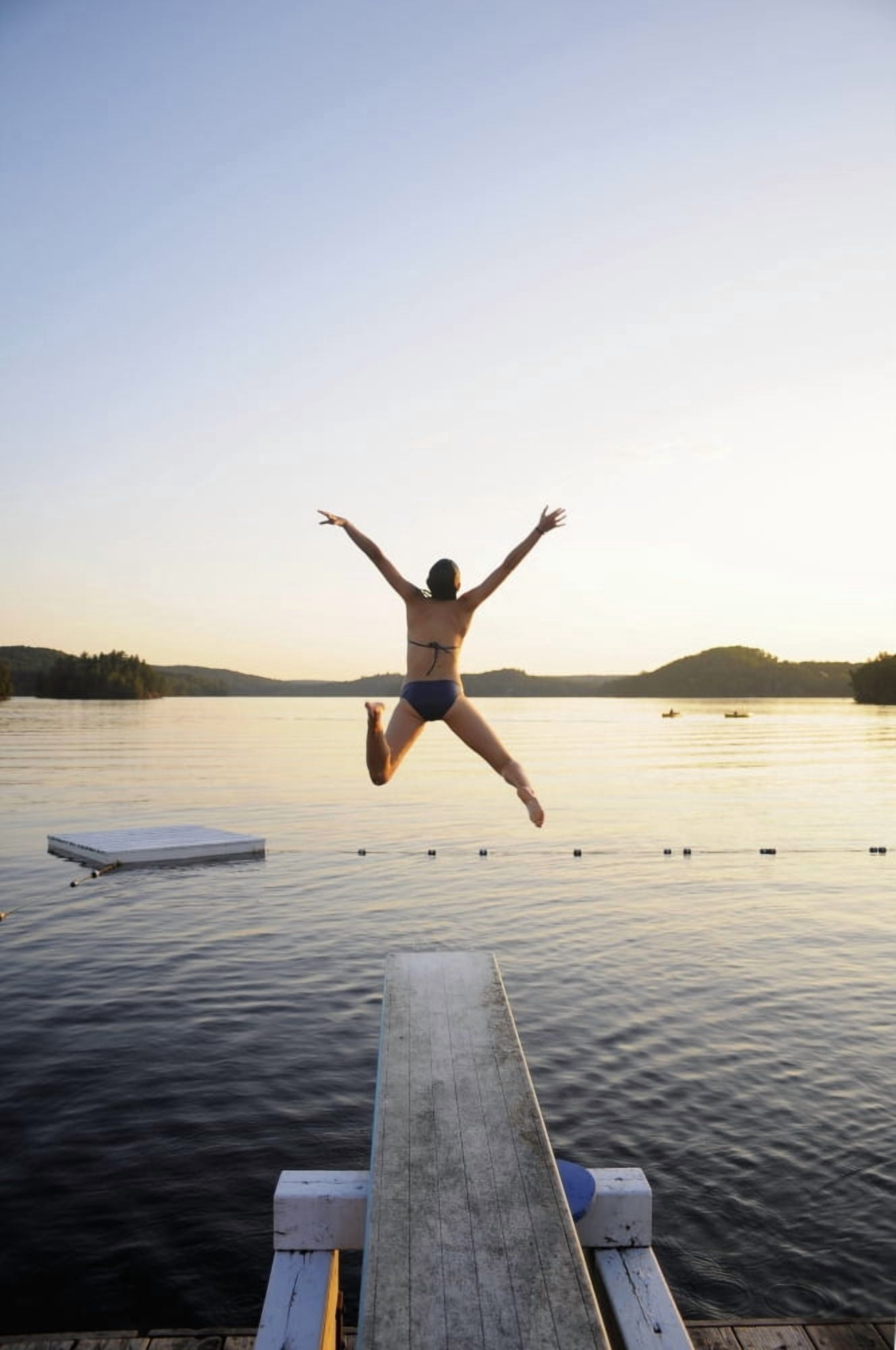 A swimmer jumps off a diving board as the sun sets over a lake in Muskoka Huntsville Ontario Canada Canvas Art - James MacDonald Design Pics (24 x 38)