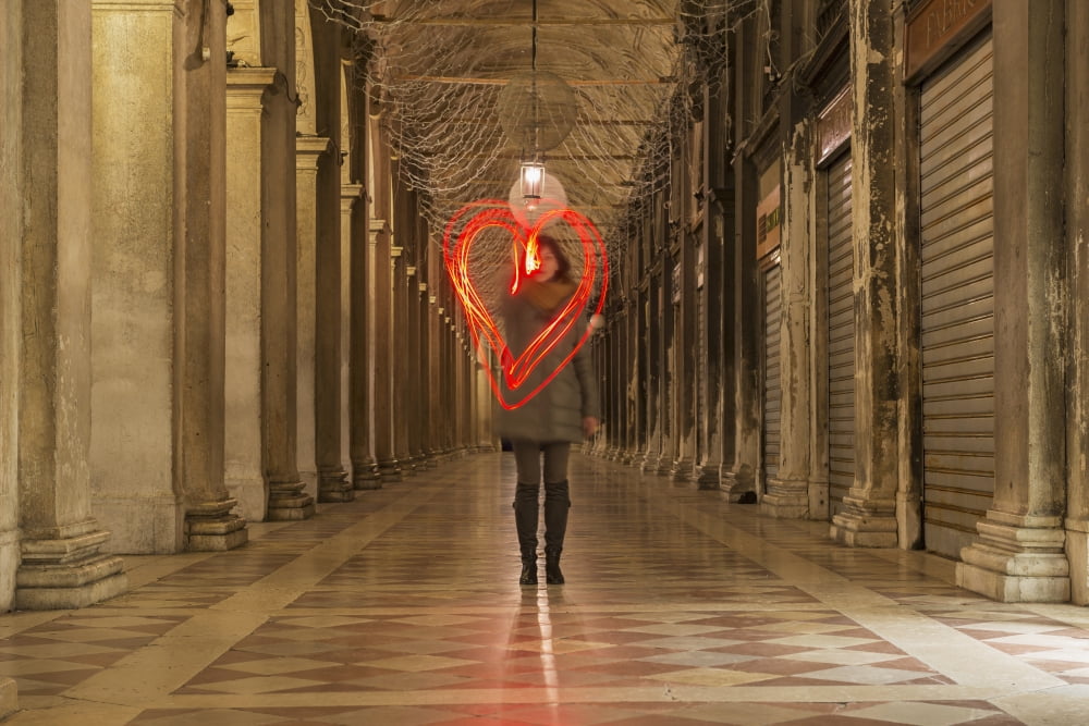 A woman walking in a corridor making a red heart shape in the air with light trails Venice Veneto Italy Canvas Art - Mats Silvan Design Pics (38 x 24)